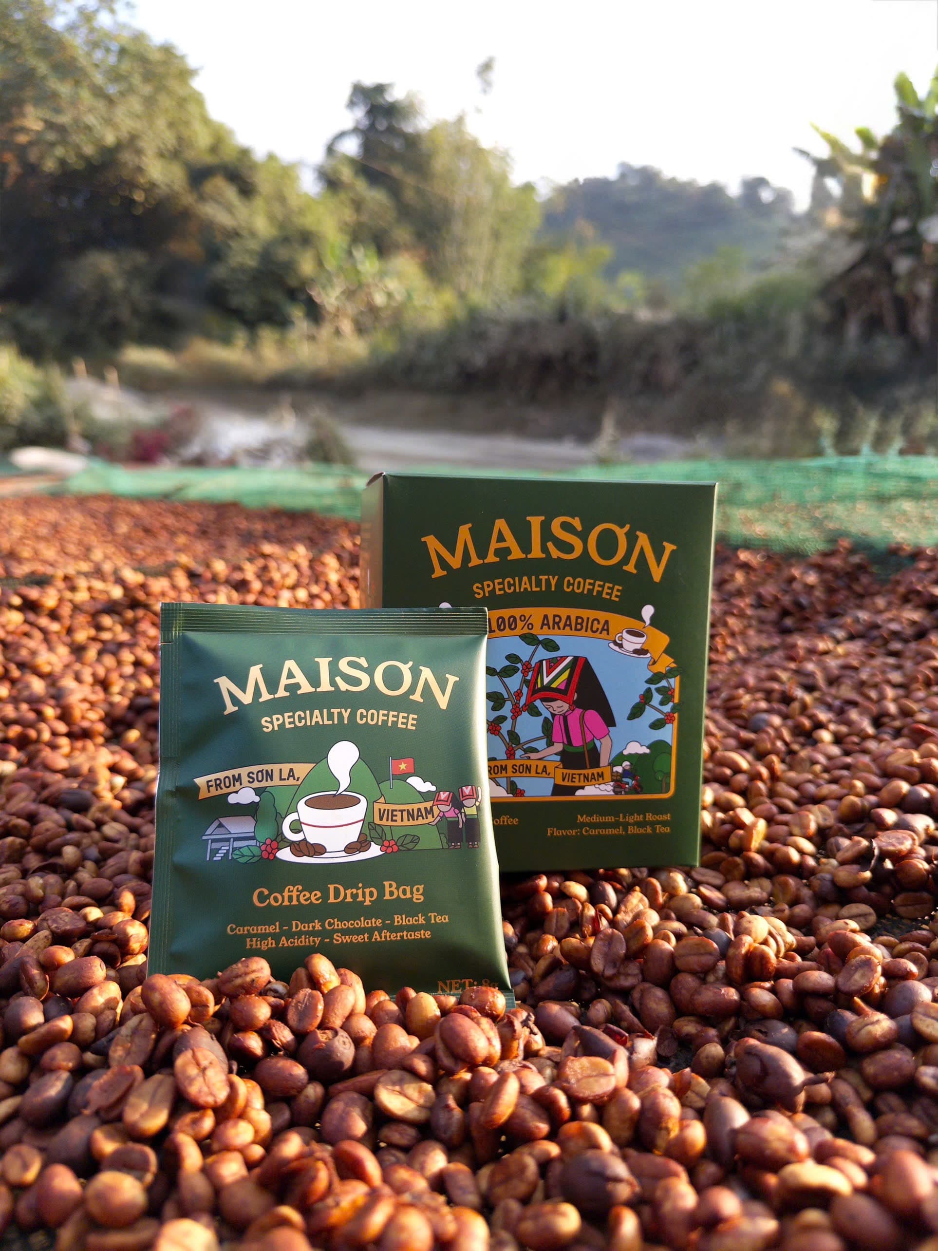 Maison Specialty drip coffee bag and box standing on honey-processed cherries drying in the highland sun
