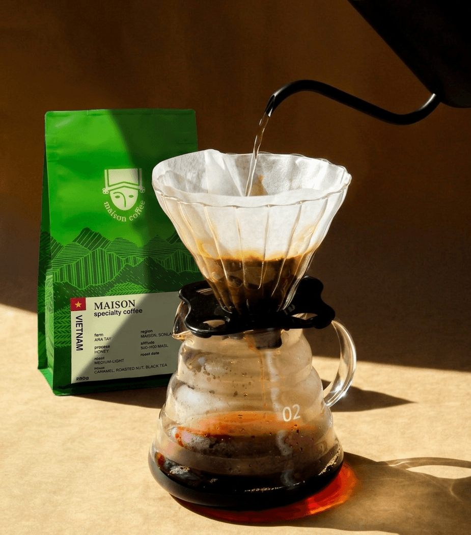 Pour-over brewing of Maison Specialty coffee beside the whole bean bag